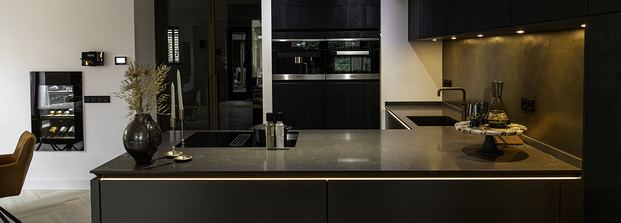 De compacte keuken met schiereiland heeft robuuste, houten panelen die zwart zijn afgelakt.
